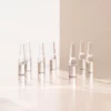 Plusieurs ampoules « Collagen Booster » de BABOR sont posées sur une surface claire, baignées d'une lumière chaude ; image d'ambiance