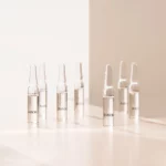 Mehrere BABOR Collagen Booster Ampullen stehen im warmen Licht auf einer hellen Fläche, Stimmungsbild