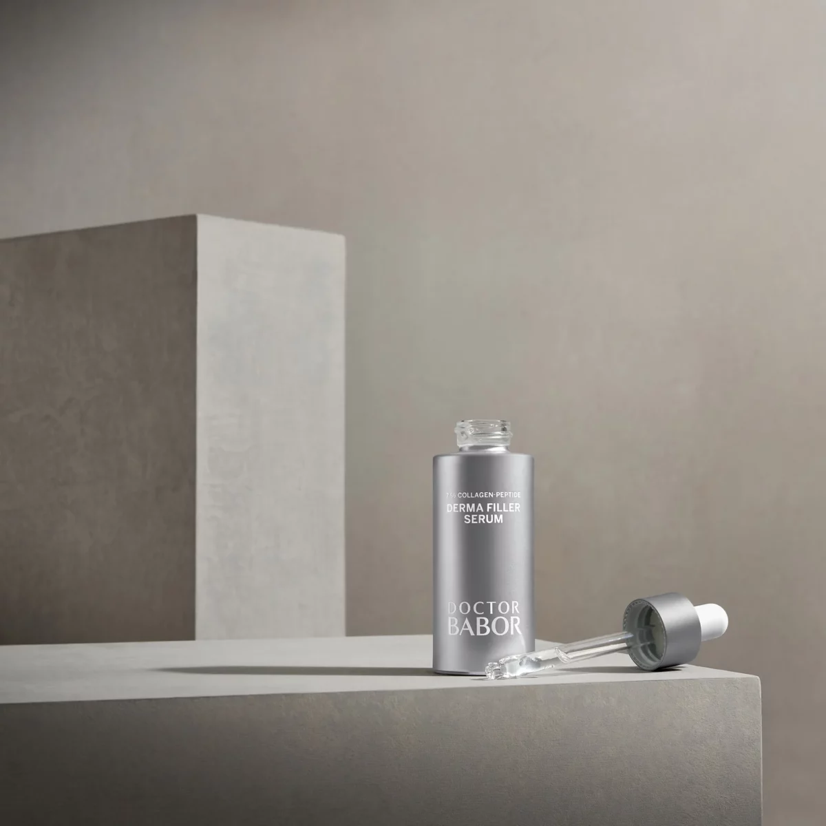 BABOR Derma Filler Serum mit herausgezogener Pipette auf grauen Steinquadern, Stimmungsbild in Grau