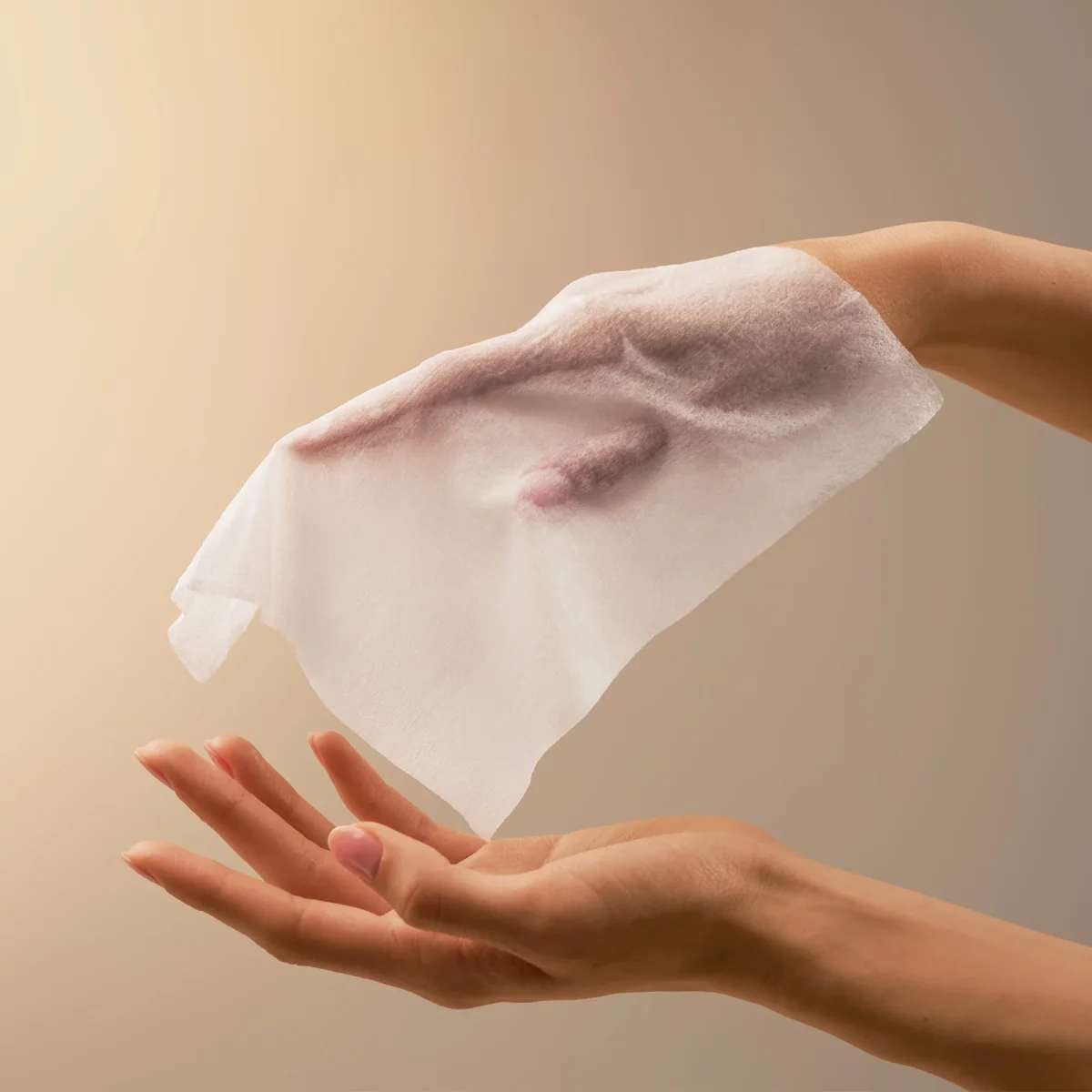 Ein BABOR Oil Infused Cleansing Wipe schwebt über einer offenen Hand, das Reinigungstuch im Einsatz
