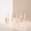 Plusieurs ampoules BABOR Perfect Glow sont posées sur une surface claire, baignées par la lumière chaude du soleil ; photo d'ambiance