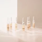 Mehrere BABOR Perfect Glow Ampullen stehen im warmen Sonnenlicht auf einer hellen Fläche, Stimmungsbild