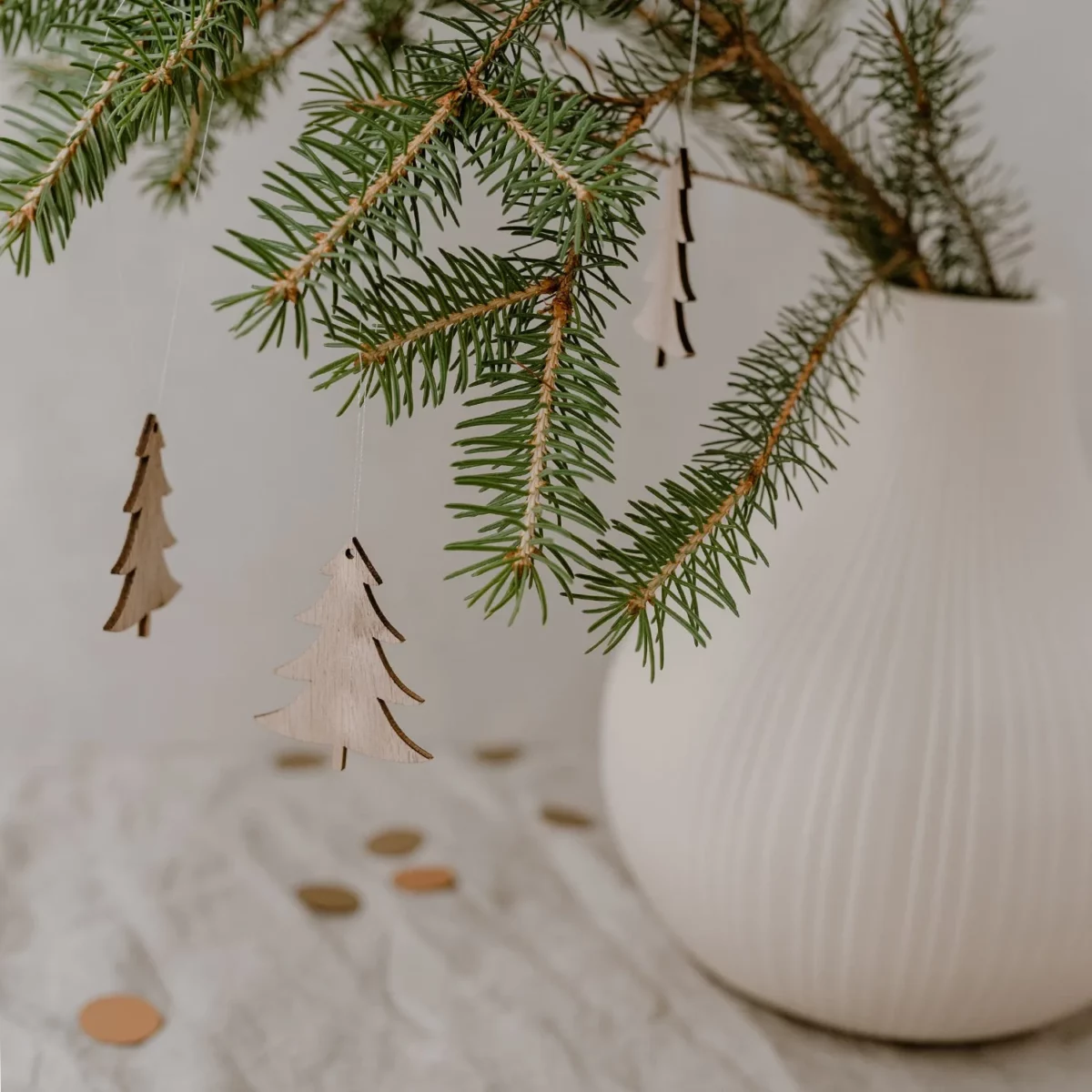 Eulenschnitt wooden fir tree ornament in natural finish, displayed on fresh fir branches in a white grooved vase on linen