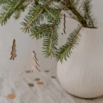 Eulenschnitt wooden fir tree ornament in natural finish, displayed on fresh fir branches in a white grooved vase on linen