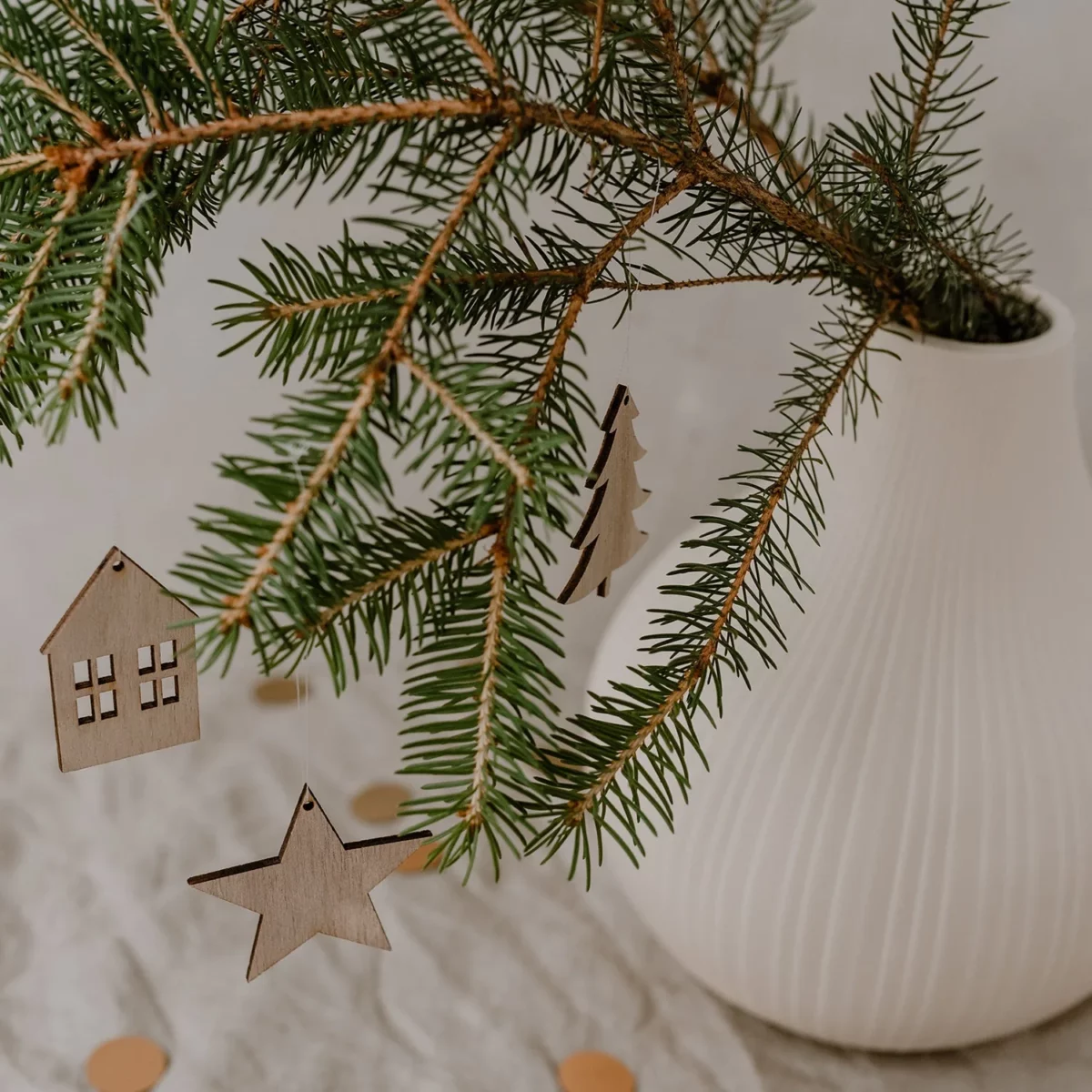 "Eulenschnitt" natural fir tree wooden pendant on a fir branch, alongside a star and house wooden pendant from the same series