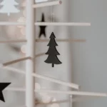 Eulenschnitt wooden fir tree ornament in black on a decorative tree made of wooden sticks, with stars and candlelight in the background