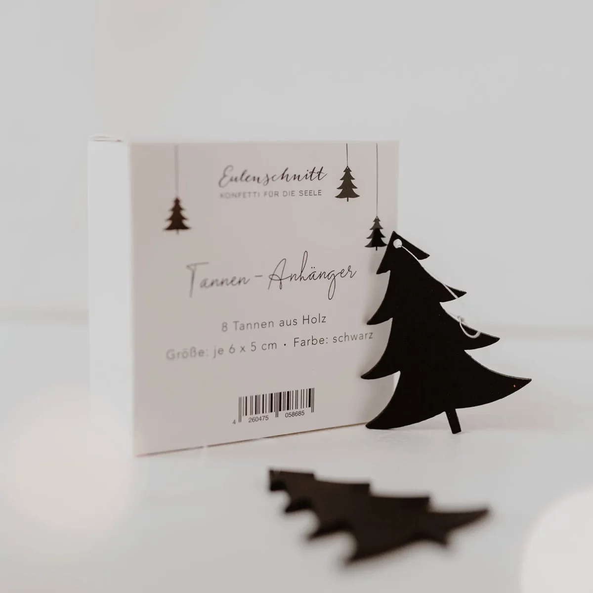 Packaging for the Eulenschnitt wooden fir tree pendants (set of 8) in black, labeled 6 x 5 cm, with two black fir trees in the foreground