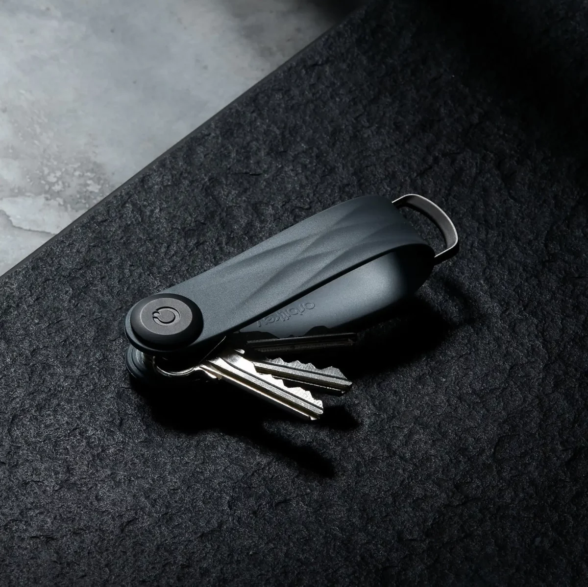 Porte-clés Orbitkey « Aktiv » en graphite sur pierre foncée, clés à moitié déployées
