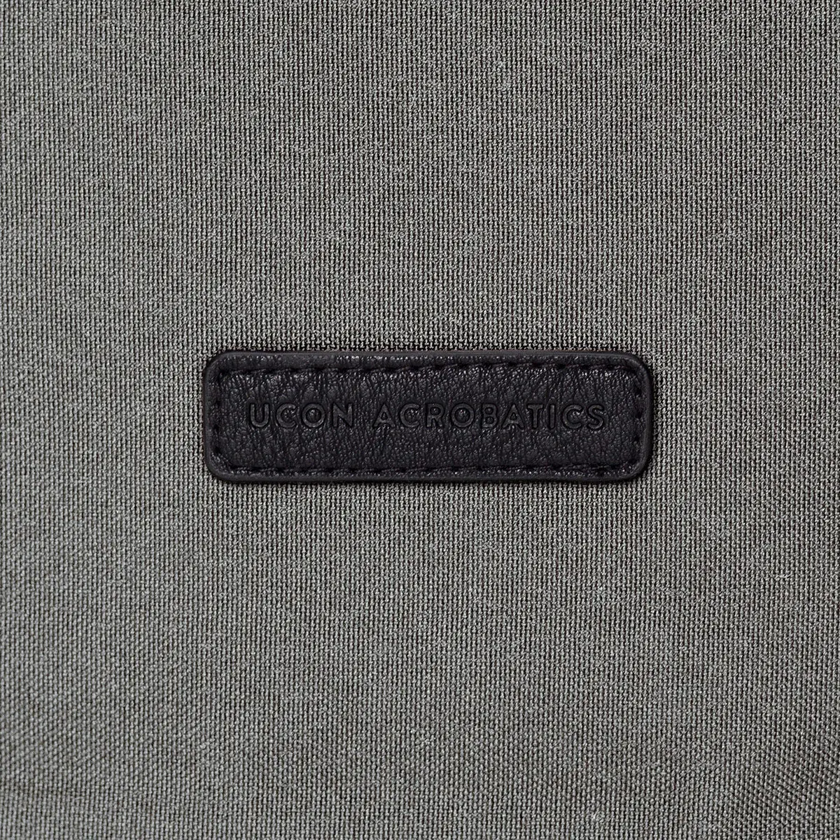 Étiquette Ucon Acrobatics en relief sur la matière PU grise du sac à dos Hajo Medium de la Stealth Series