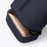 Open bottom compartment of the Ucon Acrobatics Hajo Pro backpack in dark navy holding a sneaker, apart from the main bag