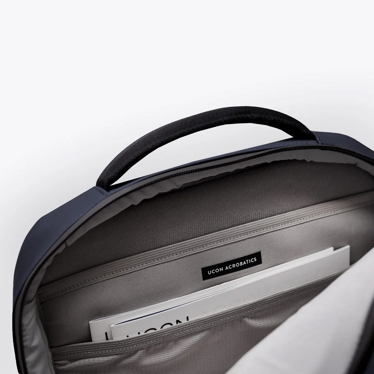 Inside the main compartment of the Ucon Acrobatics Hajo Pro backpack in dark navy with laptop sleeve and brand label