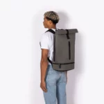 Man wearing the Ucon Acrobatics Hajo Pro backpack in dark grey, side view showing its size on the back