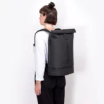 Woman wearing the Ucon Acrobatics Hajo Pro backpack in black, photographed from the side and behind