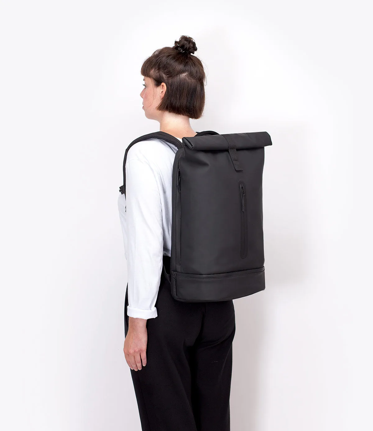 Woman wearing the Ucon Acrobatics Hajo Pro backpack in black, photographed from the side and behind