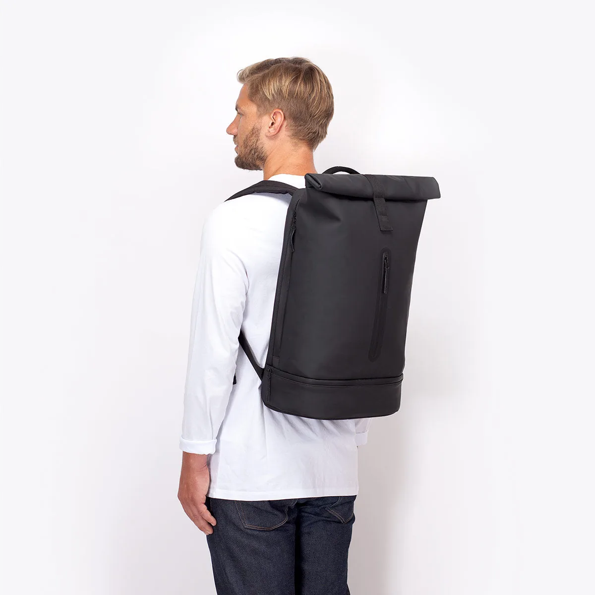 Man wearing the Ucon Acrobatics Hajo Pro backpack in black, side view showing its size on the back