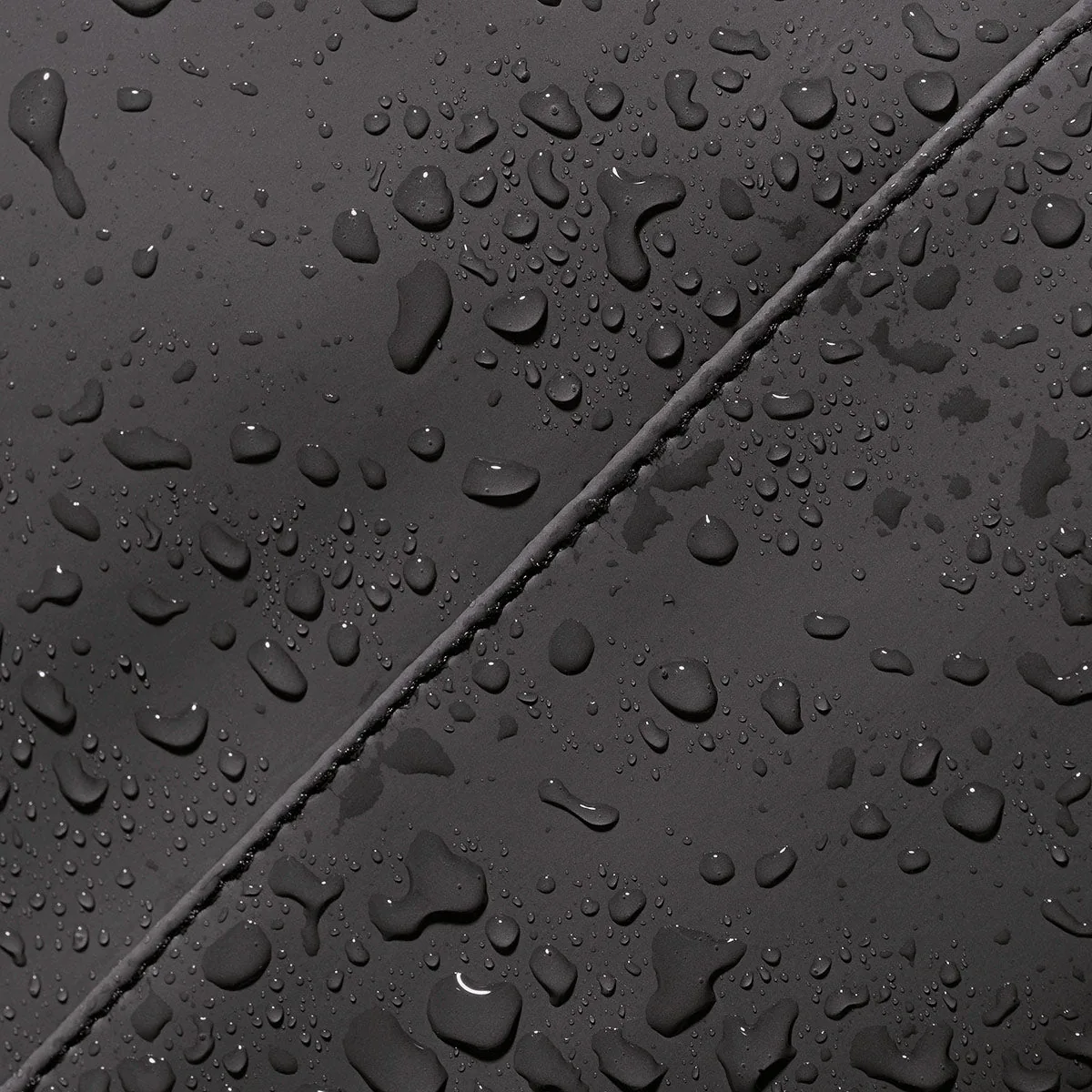 Water droplets on the water-repellent PU material of the Ucon Acrobatics Hajo Pro in black, close-up of a seam