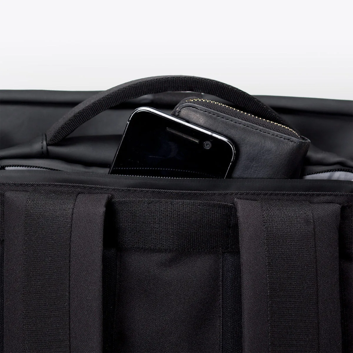 Pocket at the top of the back panel of the Ucon Acrobatics Hajo Pro backpack in black holding a phone and wallet